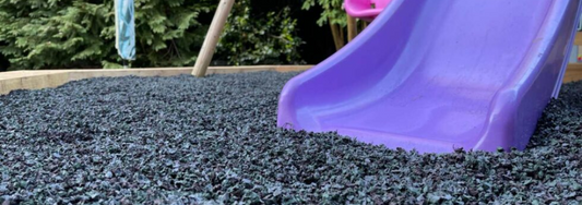 Rubber chippings underneath a purple slide in a back garden play area